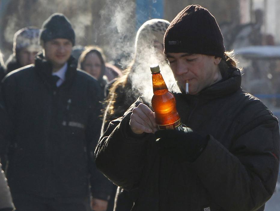 A man holds a bottle of beer while smoking with air temperature around minus 15 degrees Celsius (5 degrees Fahrenheit) in Kiev February 9, 2012. REUTERS/Gleb Garanich (UKRAINE - Tags: ENVIRONMENT SOCIETY)