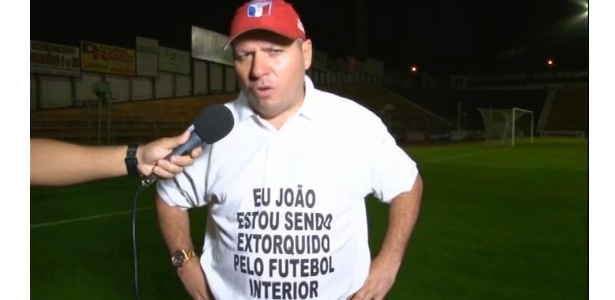 o-tecnico-e-dono-do-guaratingueta-joao-tele-utilizando-camiseta-contra-site-esportivo-do-interior-de-sp-1435082850472_615x300